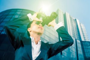 Low,Angle,View,Of,Female,Manager,Using,Binoculars,While,Standing