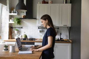 Happy,Pretty,Young,Renter,Girl,Using,Laptop,In,Modern,Kitchen.