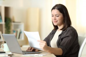 Woman,Reading,A,Letter,Using,Laptop,Sitting,In,A,Table