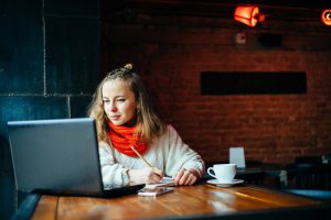 Young,Freelancer,Woman,Using,Laptop,Computer,Sitting,At,Cafe,Table.